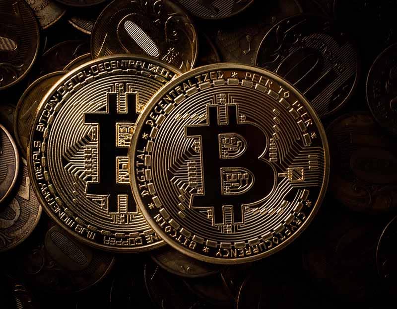 deux bitcoins en monnaie dans une image aux tons foncés